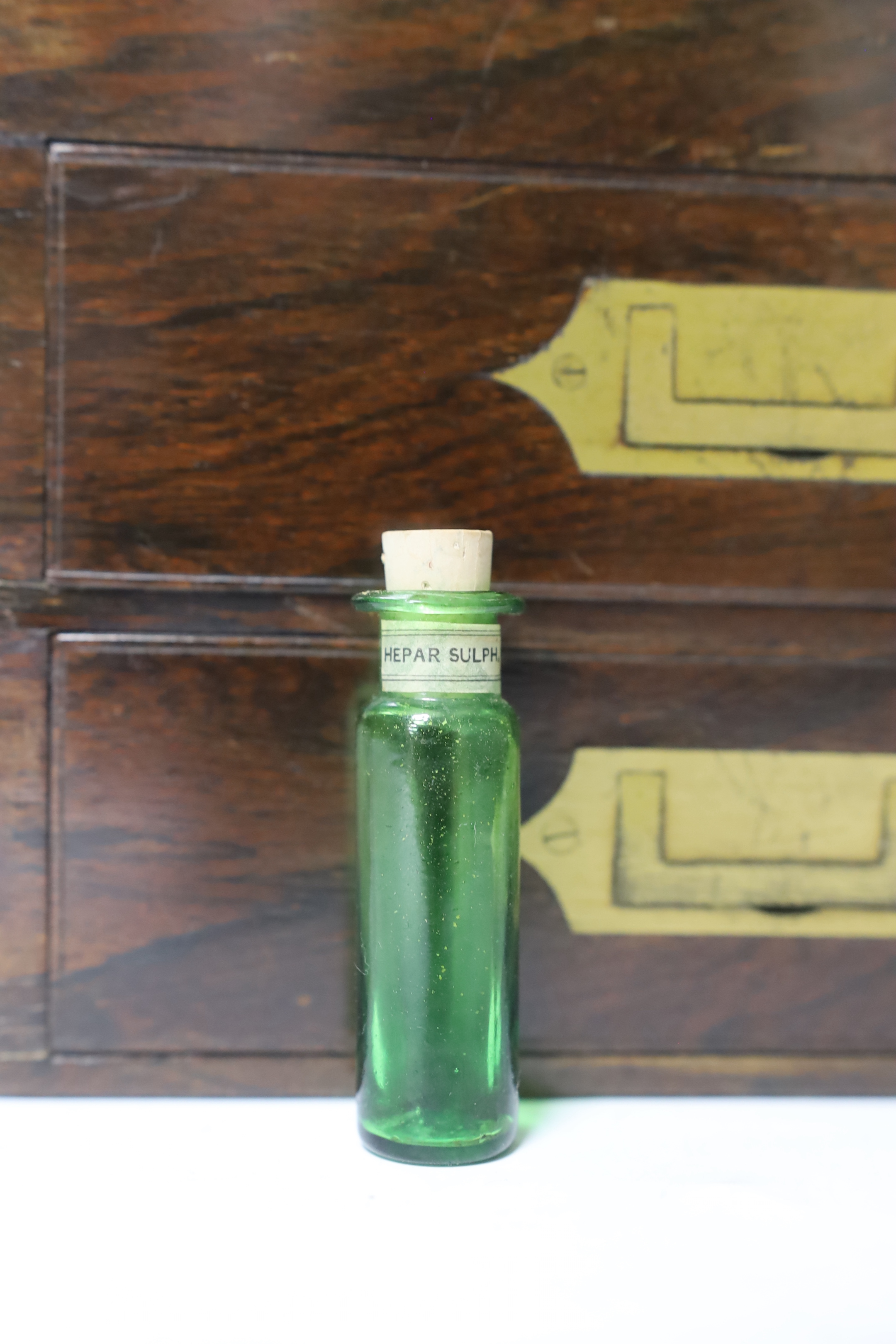 A Victorian rosewood homeopathic apothecary box, by Leath and Ross, two segmented drawers below a top opening section, containing a number of labelled chemists bottles, 21cm high, 20cm wide, 13.5cm deep